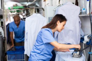 A woman meticulously irons a dress shirt for a professional.