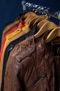 Many colors of leather jackets hanging on a rack.